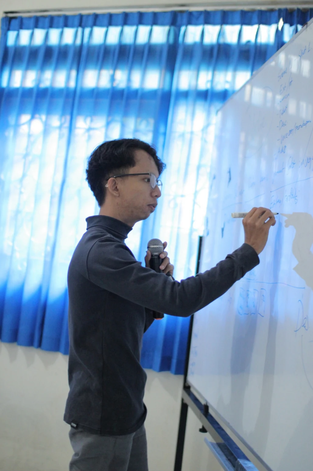 Kai writing on a whiteboard while teaching